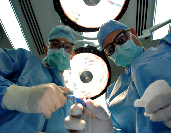 Two medical examiners looking down at operating table